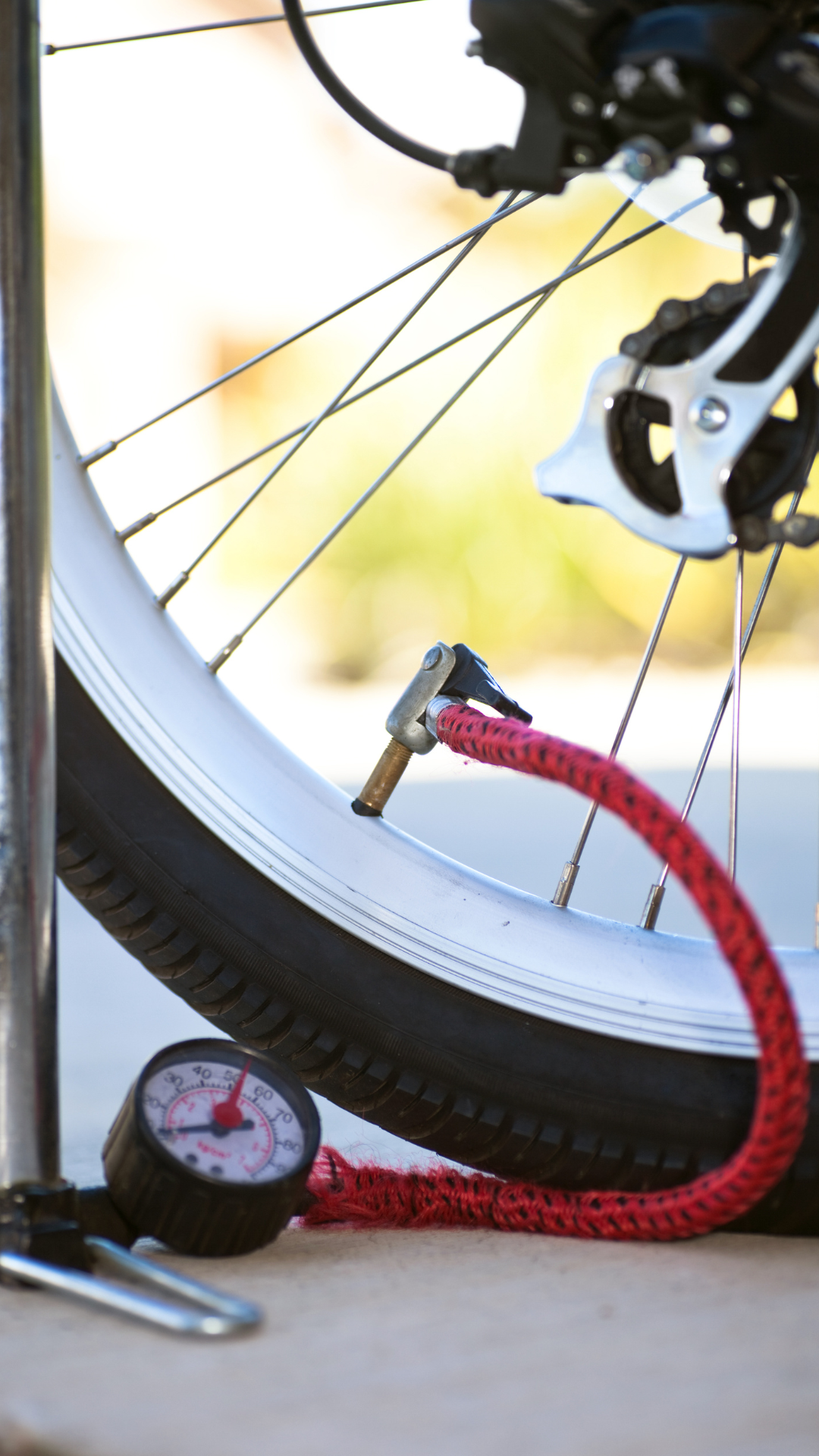 Pneu de vélo gonflé avec un tuyau rouge relié à une jauge. Le pneu est posé sur le trottoir.