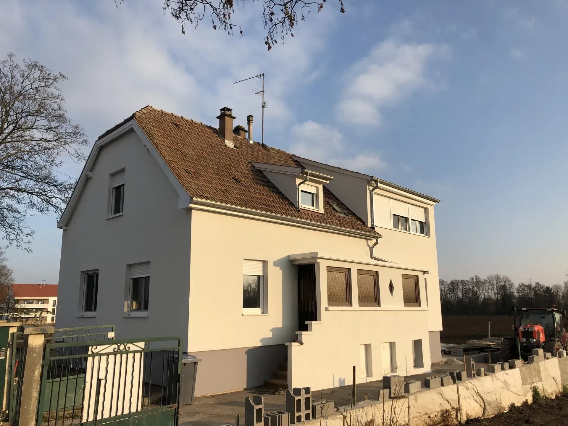 Une maison blanche avec un toit en tuile romaine