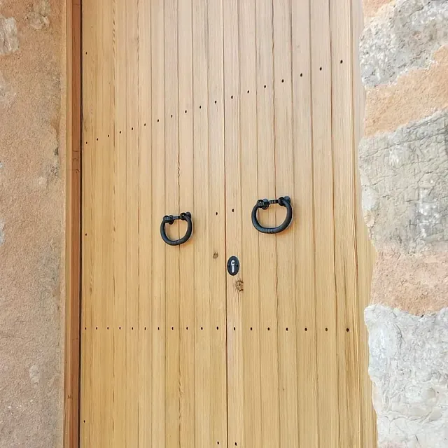 Una puerta de madera con dos manijas negras.
