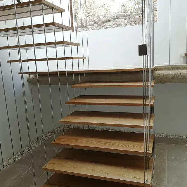 Una escalera de madera con barandilla de metal en una habitación.