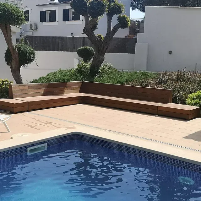 Una piscina con un sofá de madera delante de ella.