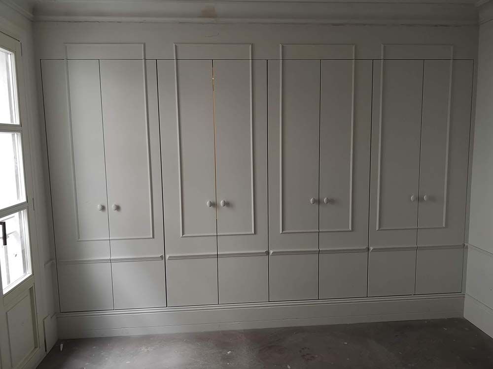 Una habitación con muchos armarios blancos en la pared.