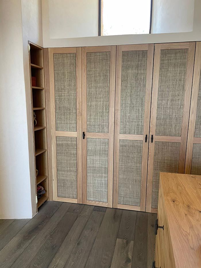 Armario de madera clara con puertas con paneles de caña tejida en una habitación con pisos de madera.