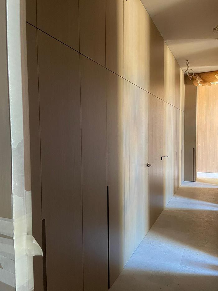 Armarios empotrados de colores claros bordean un pasillo en construcción.