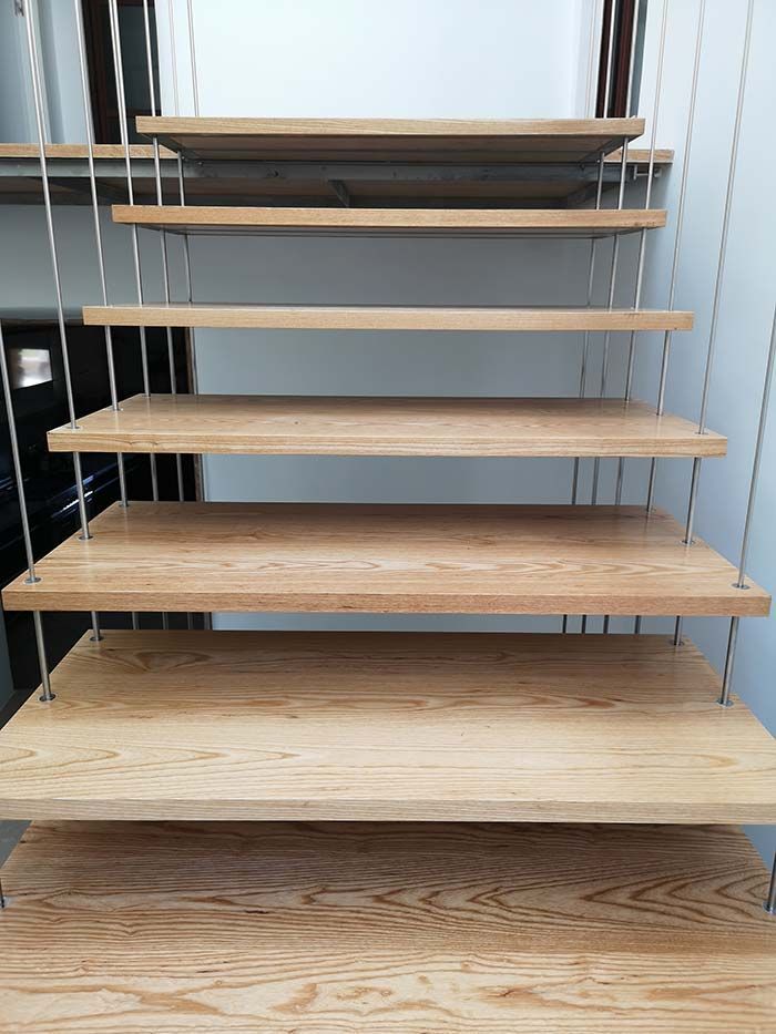 Escalera flotante de madera con barandilla de cable de acero.