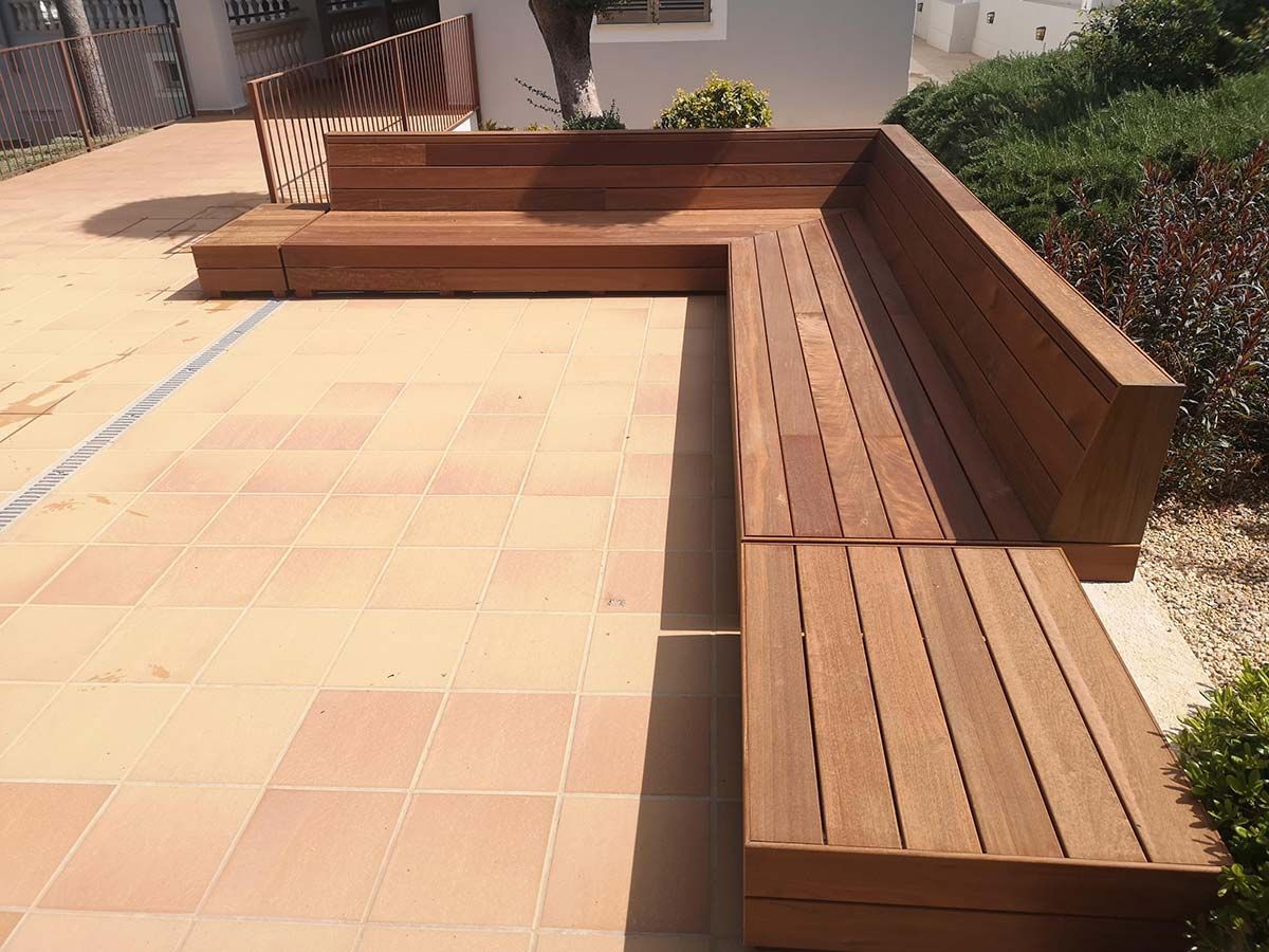 Un banco de madera está sentado en un patio de baldosas.