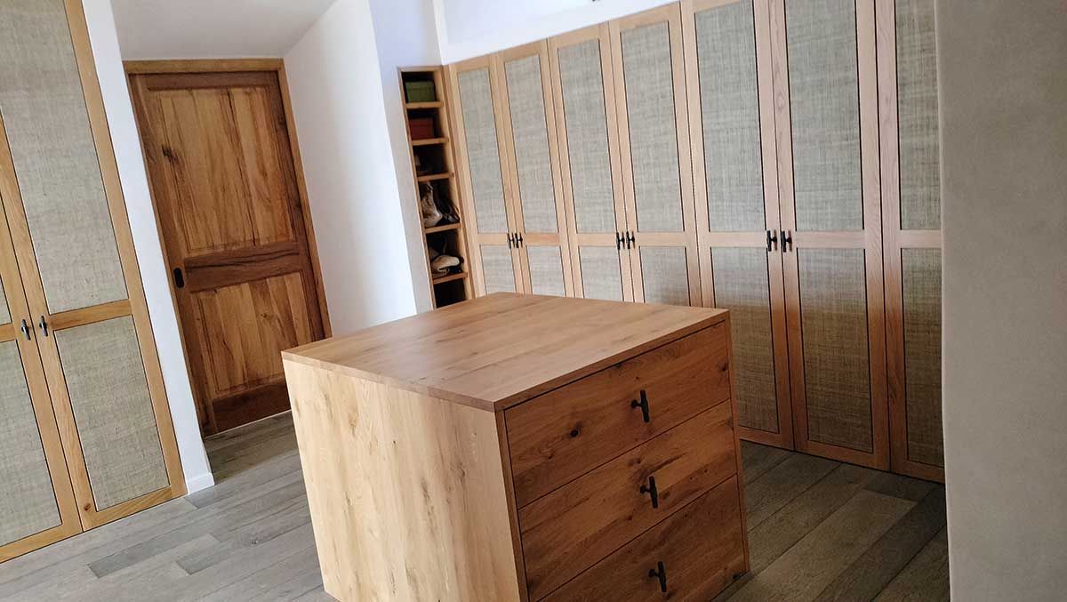 Armario de madera con cajones y puertas de paneles tejidos en una habitación con puerta de madera y estantes.