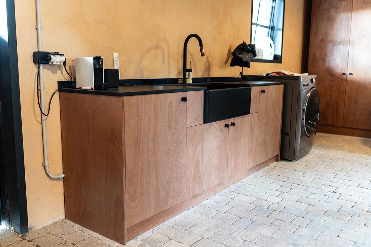 Mueble de cocina con fregadero, grifo y encimera negros. Lavadora junto al mueble.