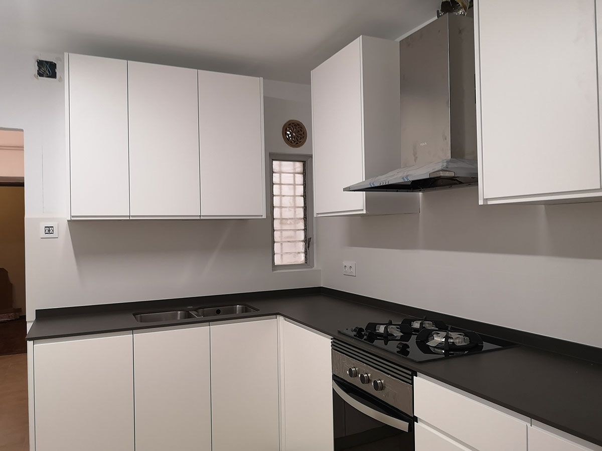 Cocina moderna con gabinetes blancos, encimera oscura, campana extractora de acero inoxidable y estufa.