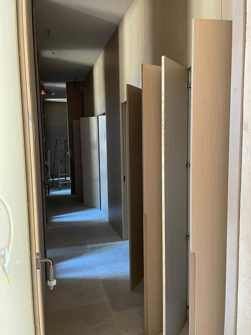 Pasillo estrecho en construcción con paredes sin terminar y puertas inclinadas.