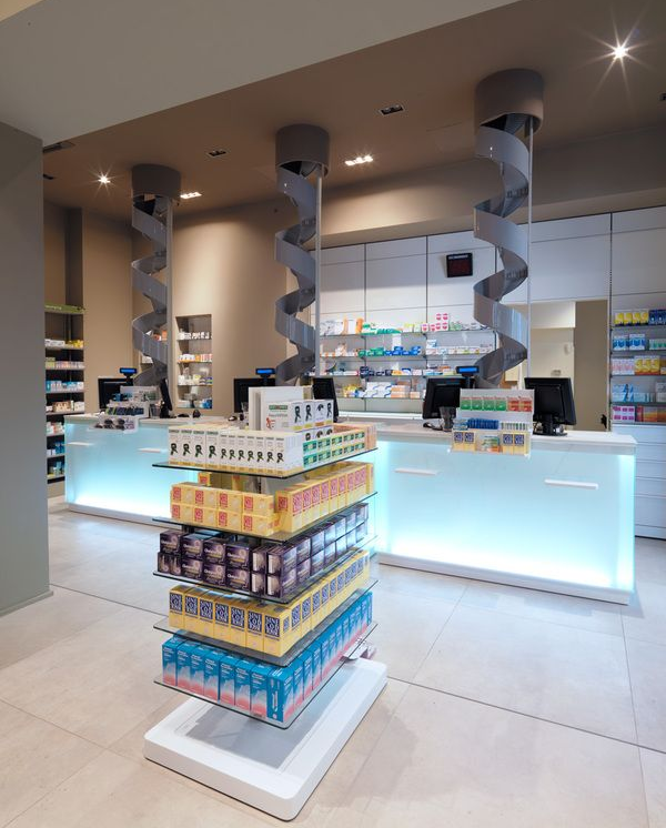 Farmacista sorridente, con in mano un blocco per appunti, in una corsia della farmacia, circondato da scaffali pieni di prodotti.