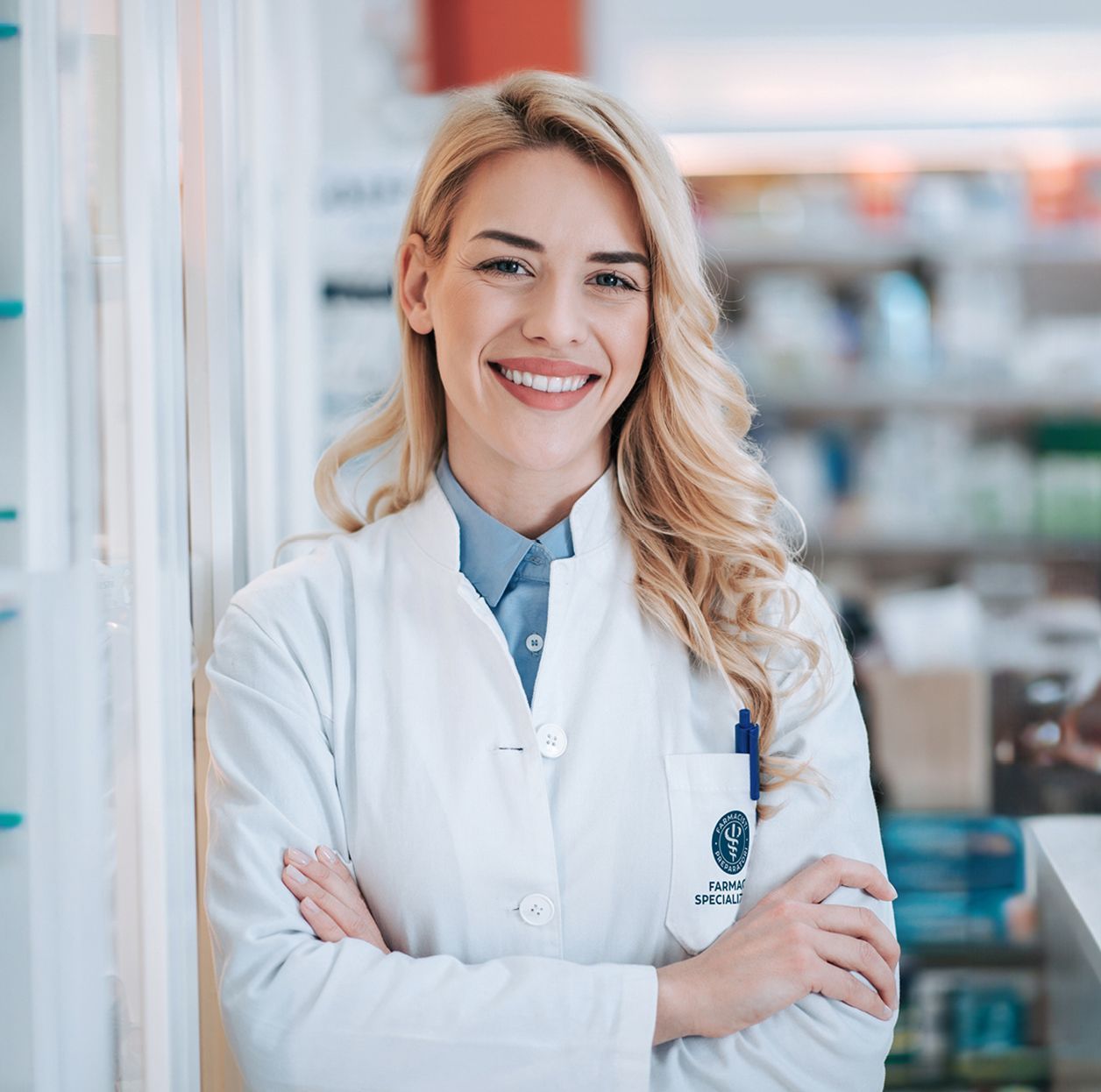 Farmacista in camice bianco che parla con un cliente in farmacia.