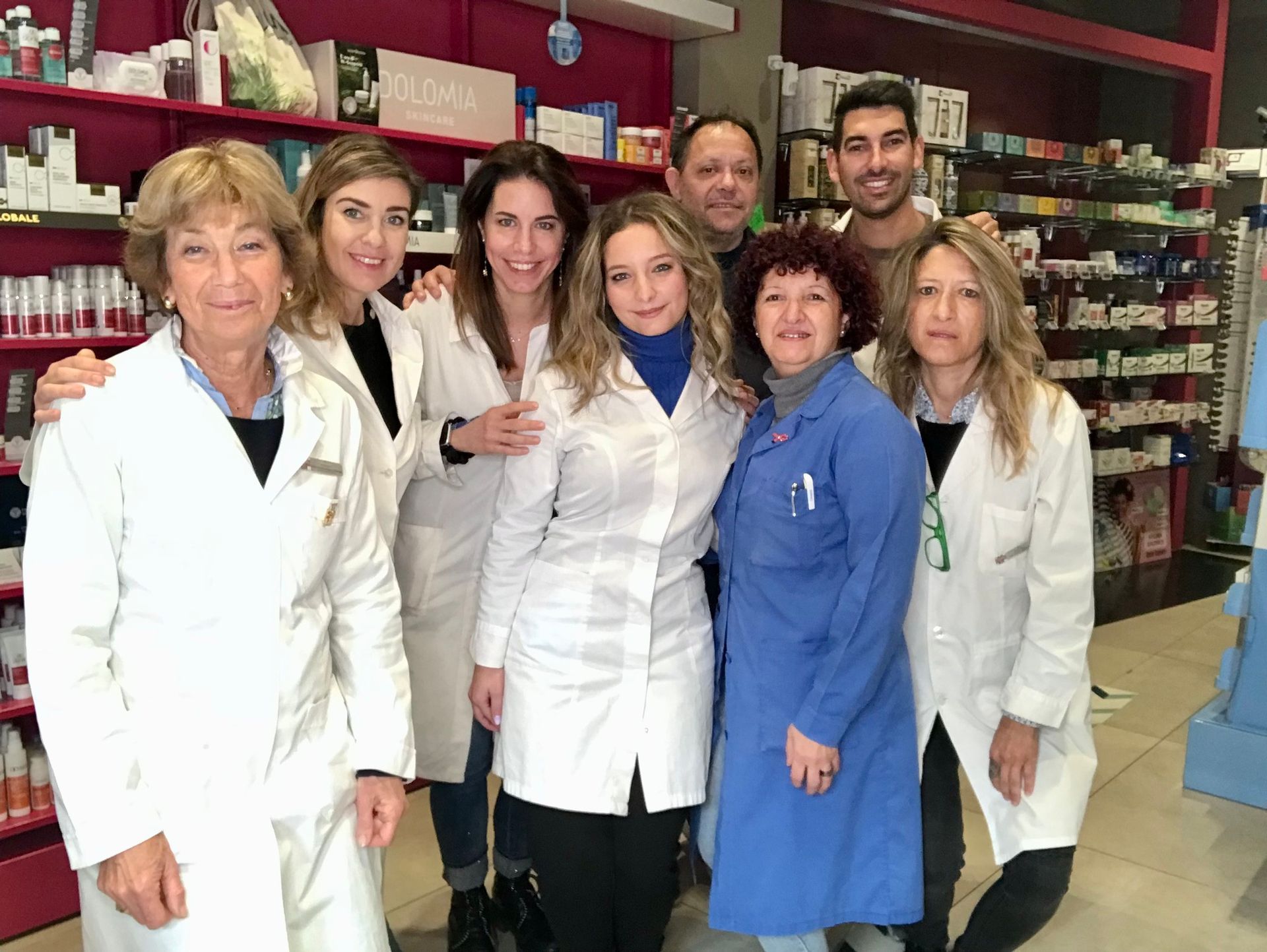 Donna in camice bianco in una farmacia, mentre controlla l'inventario dei farmaci sugli scaffali.
