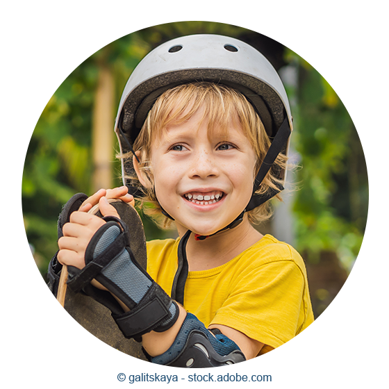 Ein kleiner Junge mit Skateboard und Helm