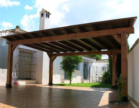 Una casa blanca con una pérgola de madera delante de ella.