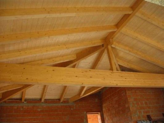 Un techo de madera con una pared de ladrillos al fondo.