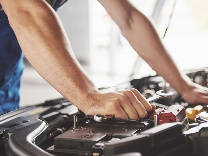 Un hombre está trabajando en el motor de un coche.