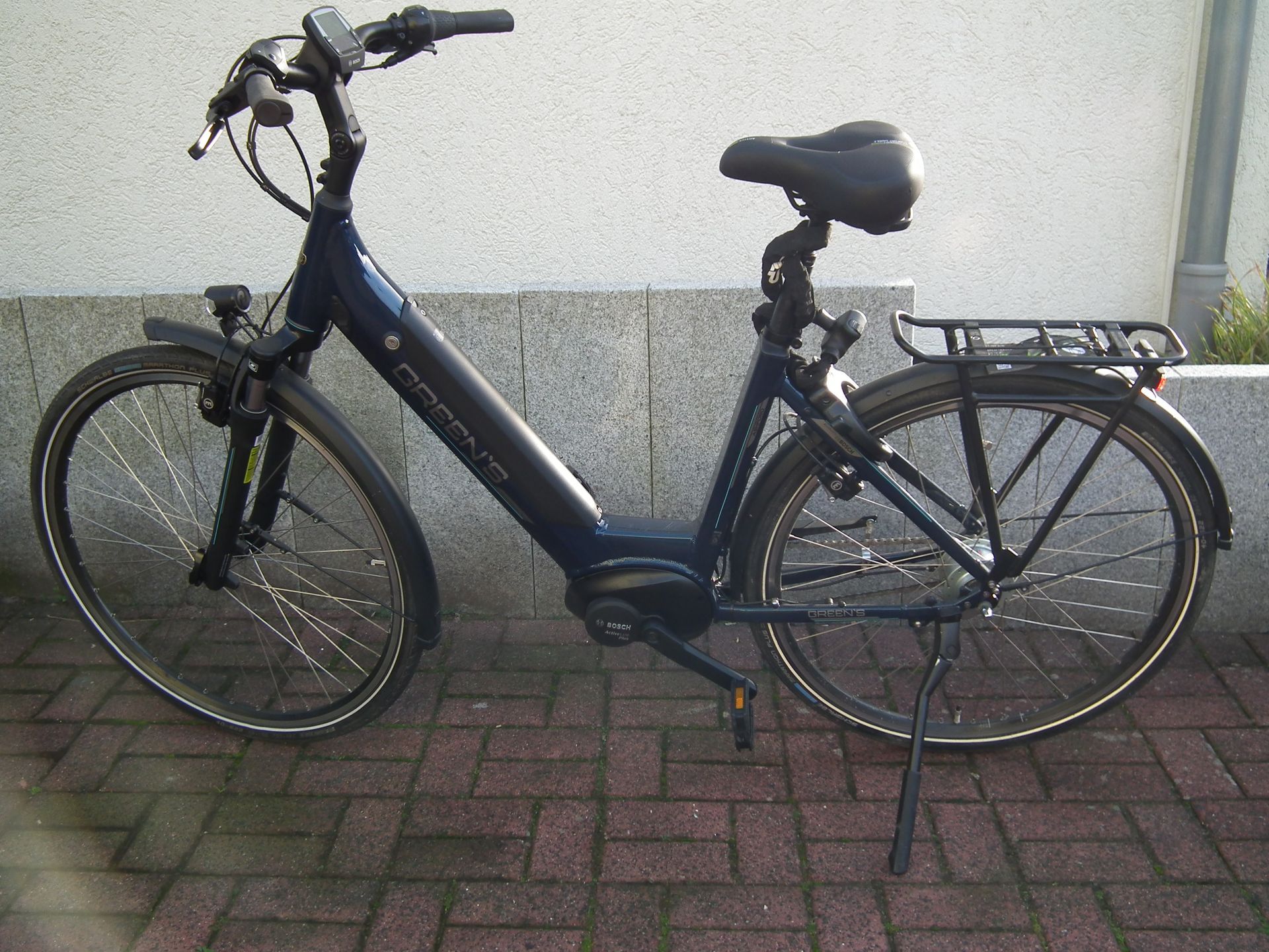 Ein blaues Fahrrad steht auf einem gepflasterten Gehweg