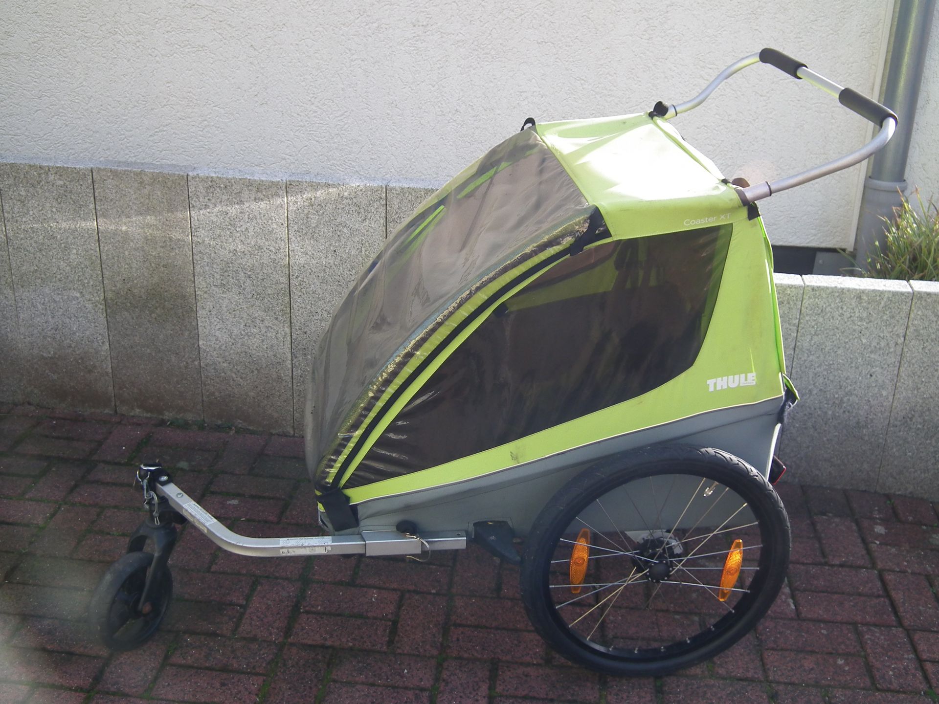 Ein grüner Kinderwagen mit dem Wort Thule darauf