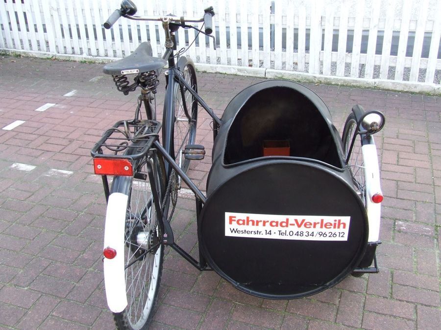 Ein Fahrrad mit Beiwagen, auf dem fahrrad-verleih steht