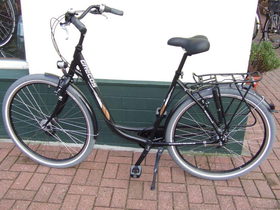 Ein schwarzes Fahrrad steht auf einem gepflasterten Gehweg