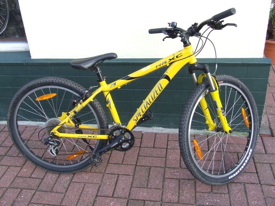 Ein gelbes Spezialfahrrad steht auf einem gepflasterten Gehweg