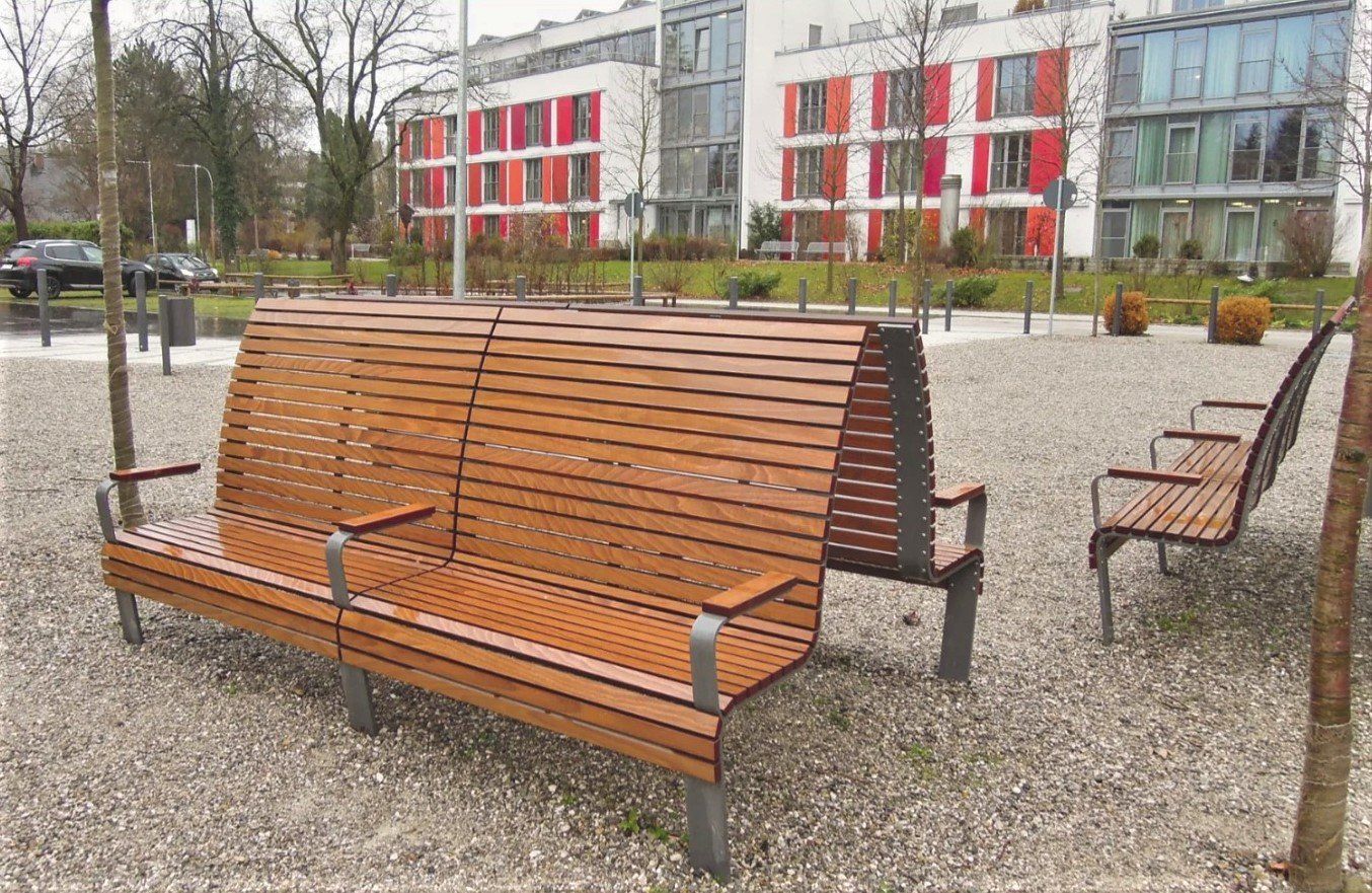Puisia penkkejä päällystetyllä aukiolla, taustalla modernit rakennukset