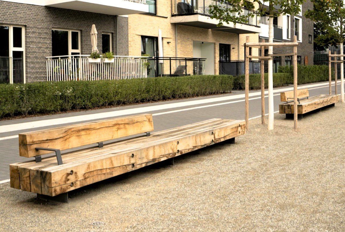 Puiset penkit sorapihalla modernien kerrostalojen ja pensasaitojen vieressä