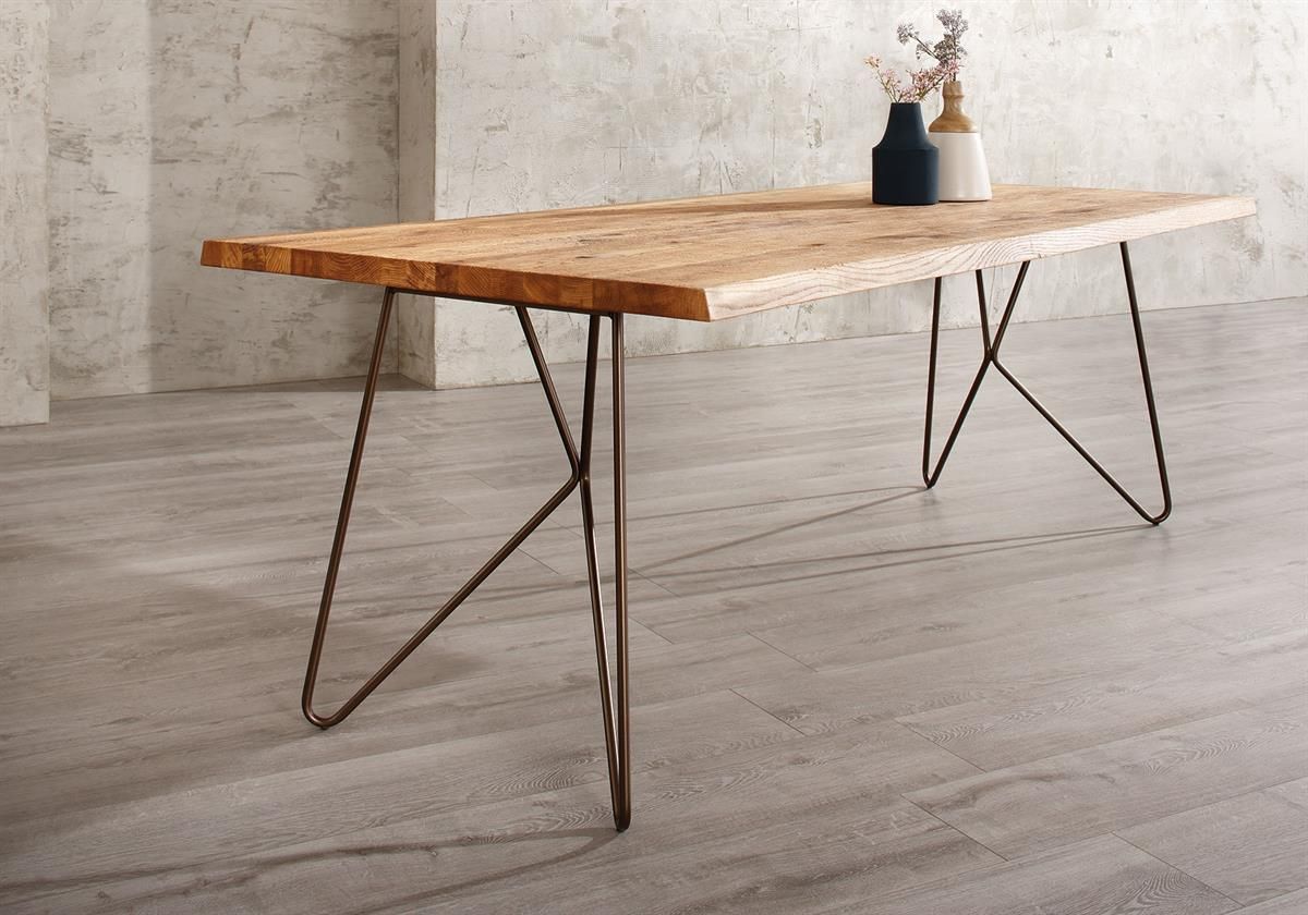 Ein Holztisch mit Metallbeinen steht auf einem Holzboden.