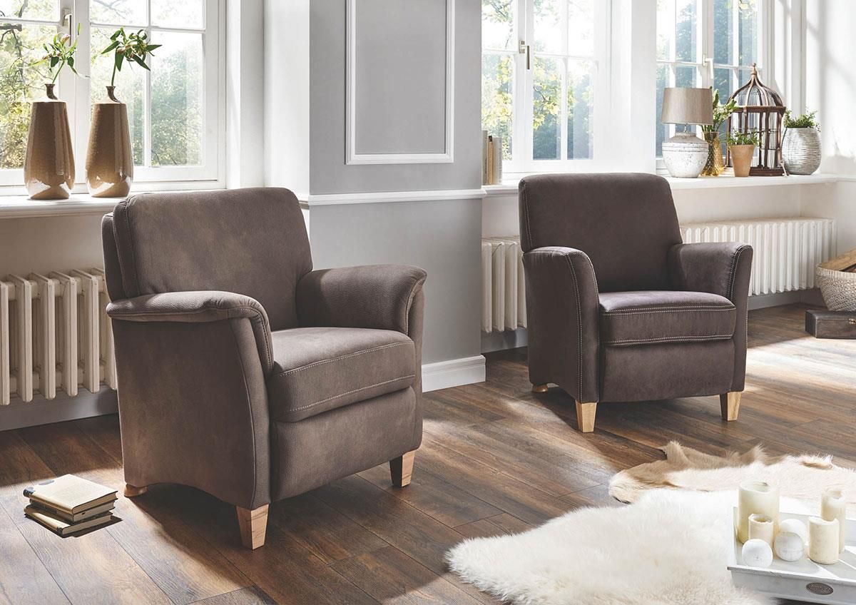 Zwei braune Stühle stehen in einem Wohnzimmer neben einem Fenster.