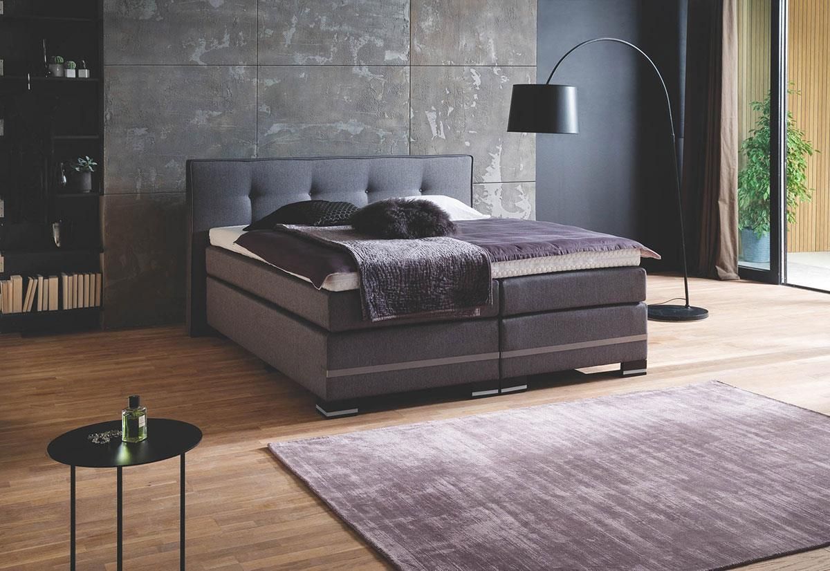 Ein Schlafzimmer mit Bett, Lampe, Tisch und Teppich.