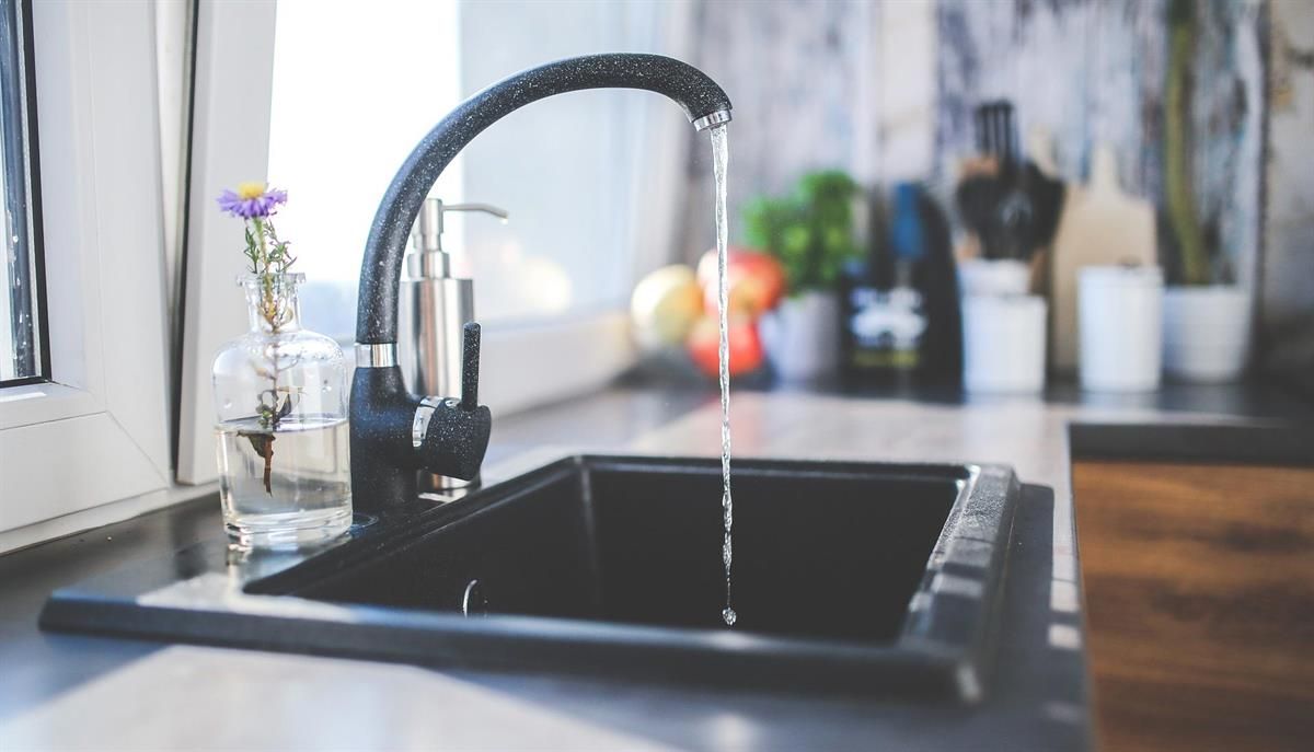 Eine Küchenspüle, aus deren Wasserhahn Wasser läuft.