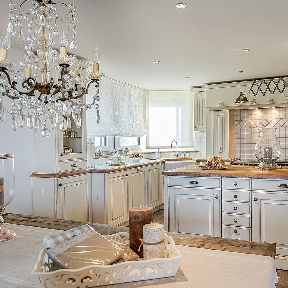 Eine Küche mit weißen Schränken und einem Kronleuchter, der von der Decke hängt