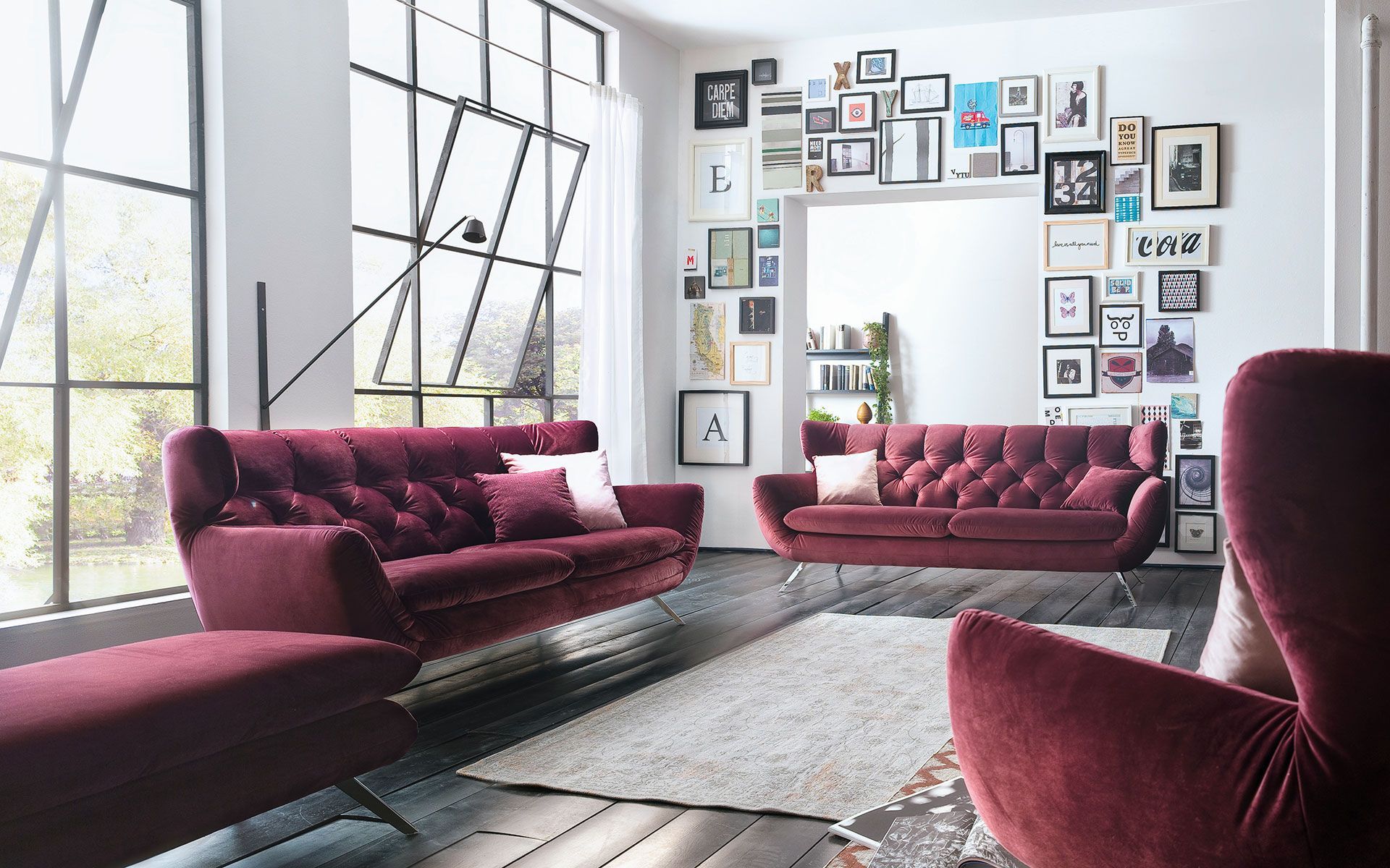 Ein Wohnzimmer mit Couch, Sessel, Teppich und Bildern an der Wand.