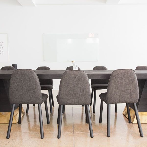 Ein Konferenzraum mit Tisch und Stühlen und einem Whiteboard.