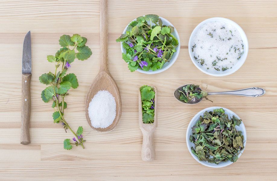 Ein Holztisch mit Schüsseln voller Kräuter, Salz und Löffeln.