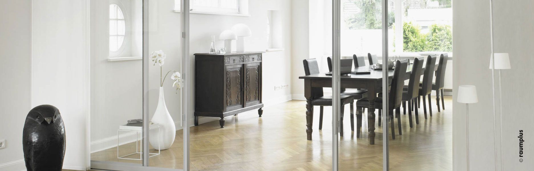 Ein Wohnzimmer mit Glasschiebetüren, die zum Esszimmer führen.