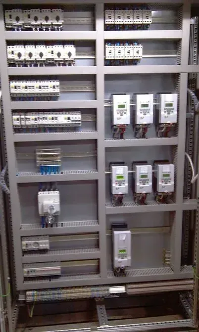 Painel de controle elétrico cinza com vários componentes, incluindo disjuntores e medidores.