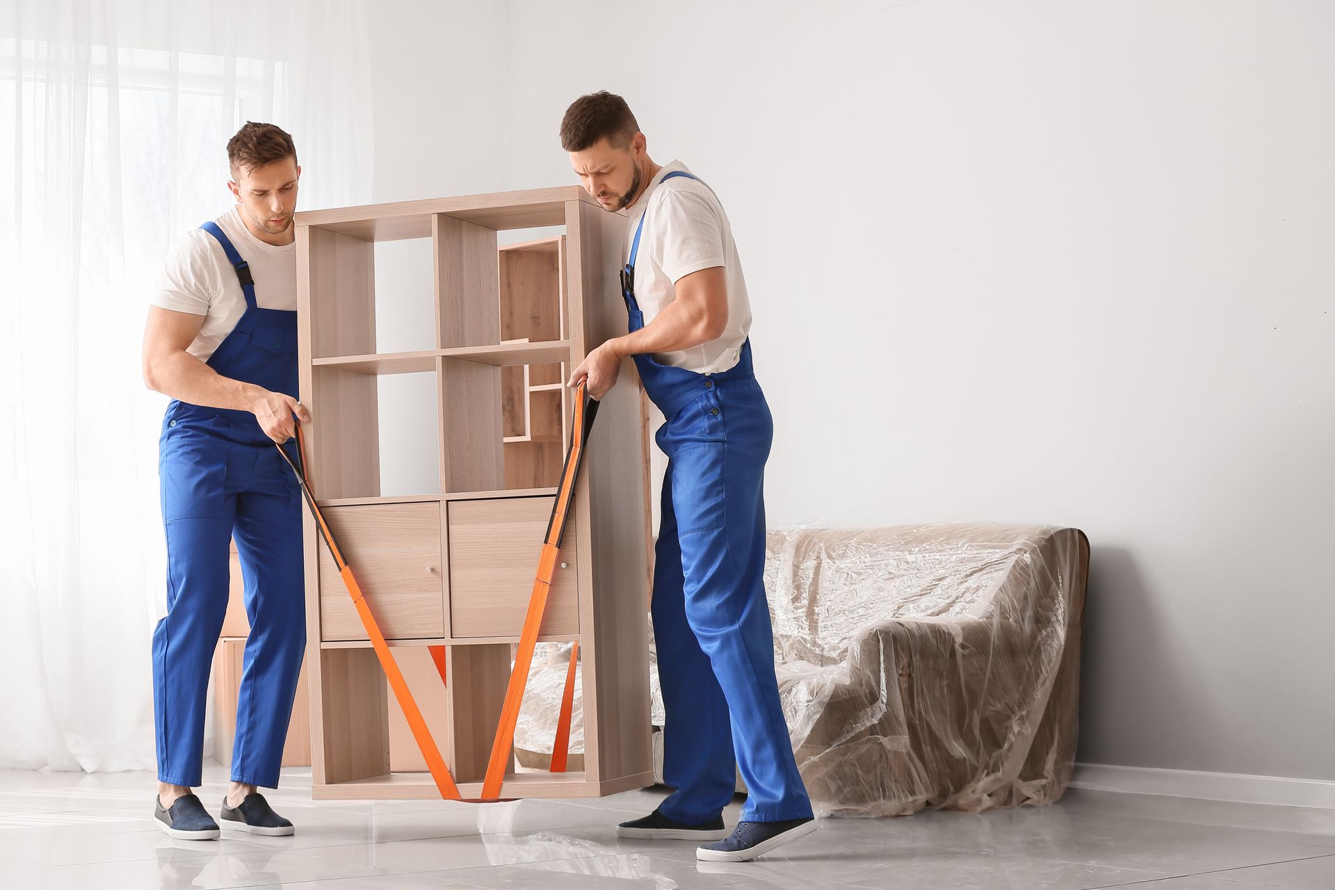 2 hommes qui portent un meuble avec des sangles