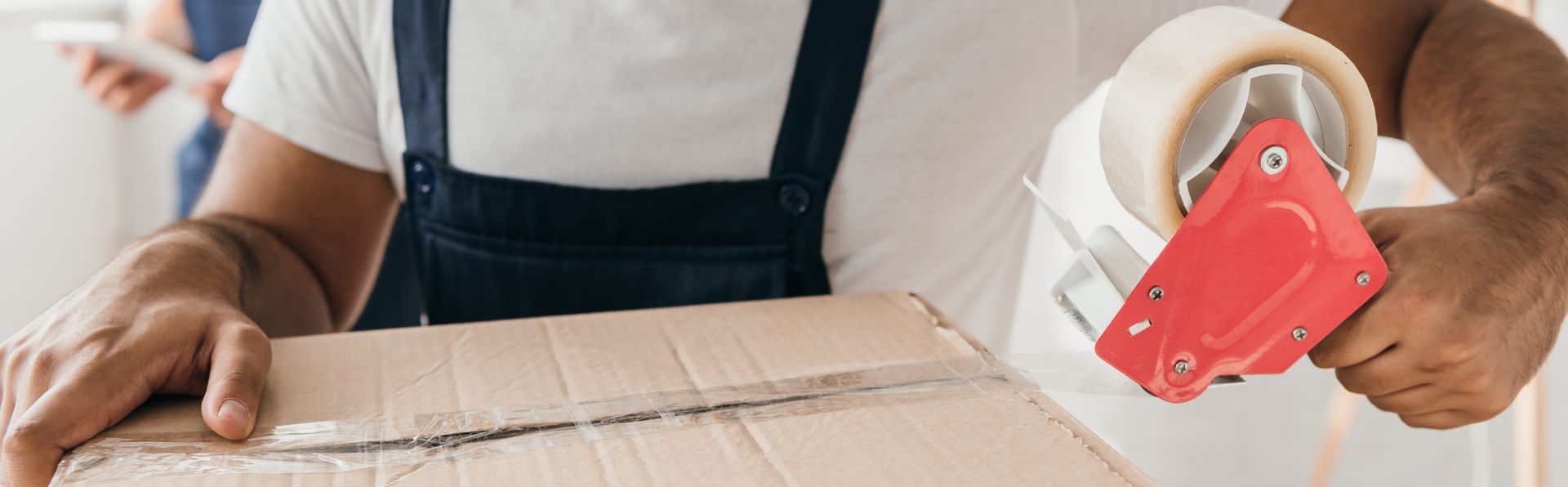Un homme qui ferme un carton avec du scotch