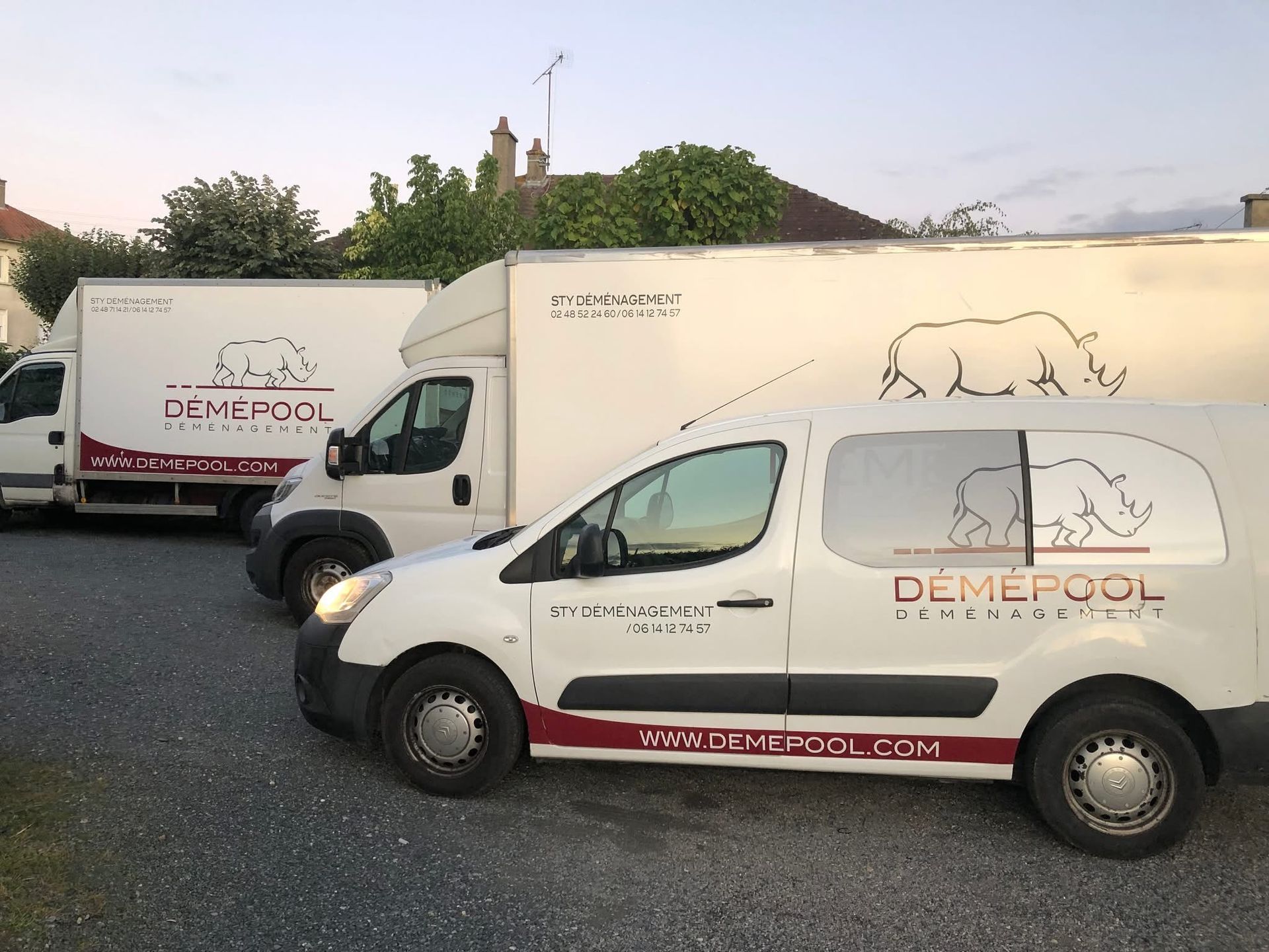Fourgonnettes blanches avec le logo « DEMEPOOL » garées devant un bâtiment.