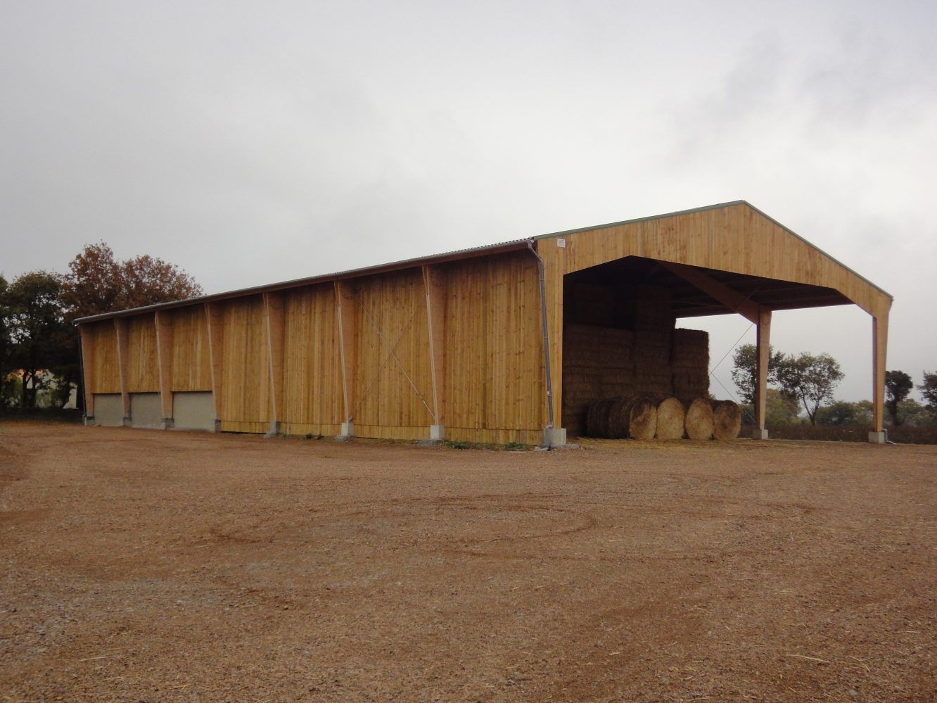 Grange agricole en bois avec des balles de foin stockées à l'intérieur.