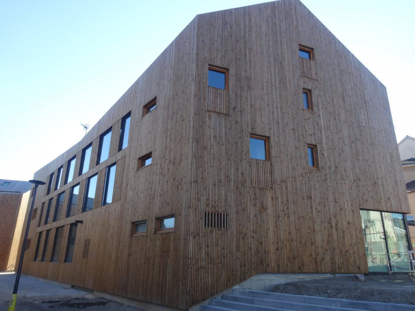 Bâtiment en bois avec de nombreuses petites fenêtres, design moderne, par une journée ensoleillée.