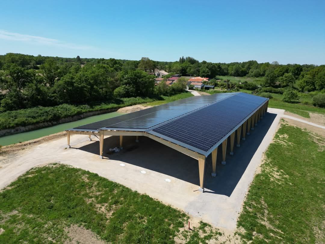 Panneaux solaires installés sur une structure en bois, au milieu d'un champ. Ciel dégagé.