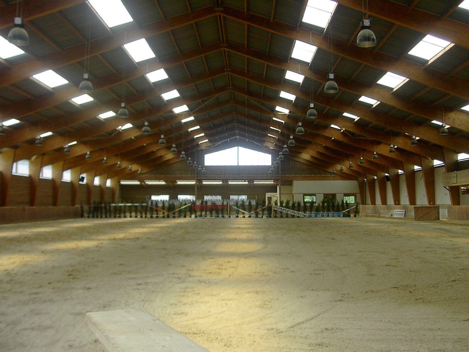 Immeuble moderne à plusieurs étages, avec bardage gris et bois, sous un ciel nuageux.