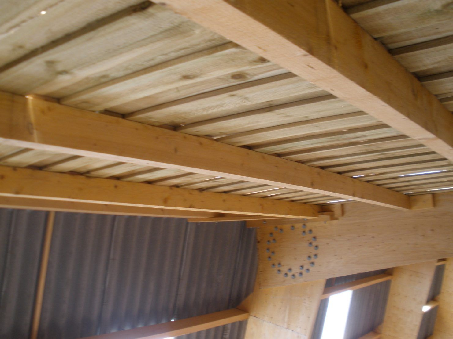 Poutres et panneaux de plafond en bois à l'intérieur d'un bâtiment, vus d'en bas.