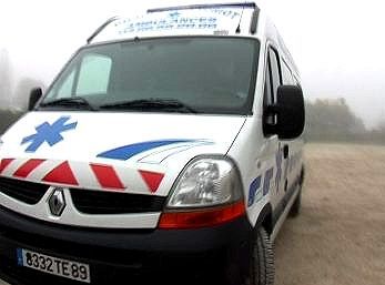 Ambulance blanche avec étoile de vie bleue et bandes rouges sur une route brumeuse
