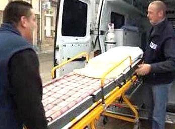Deux ambulanciers chargent un patient sur une civière dans une ambulance.