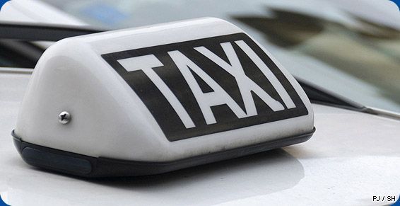 Panneau de taxi sur le toit d'une voiture, lettres noires sur fond blanc