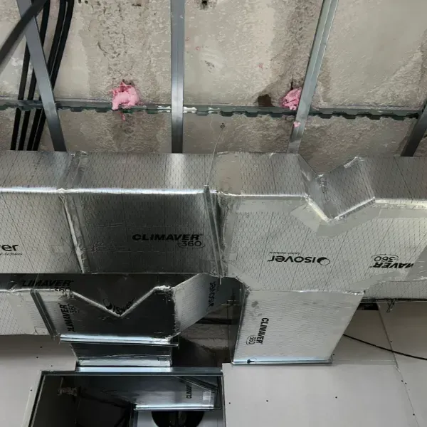 Instalación de conductos de climatización en un edificio. Los conductos plateados están parcialmente cubiertos.